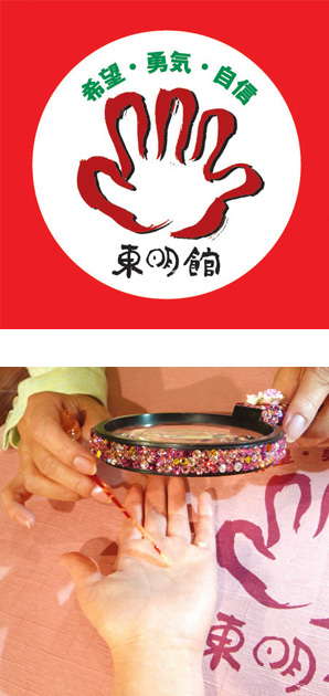 写真の上段：東明館のロゴマーク/下段：ピンクのきらきらで装飾したルーペと指し棒を使って手相占いの鑑定中